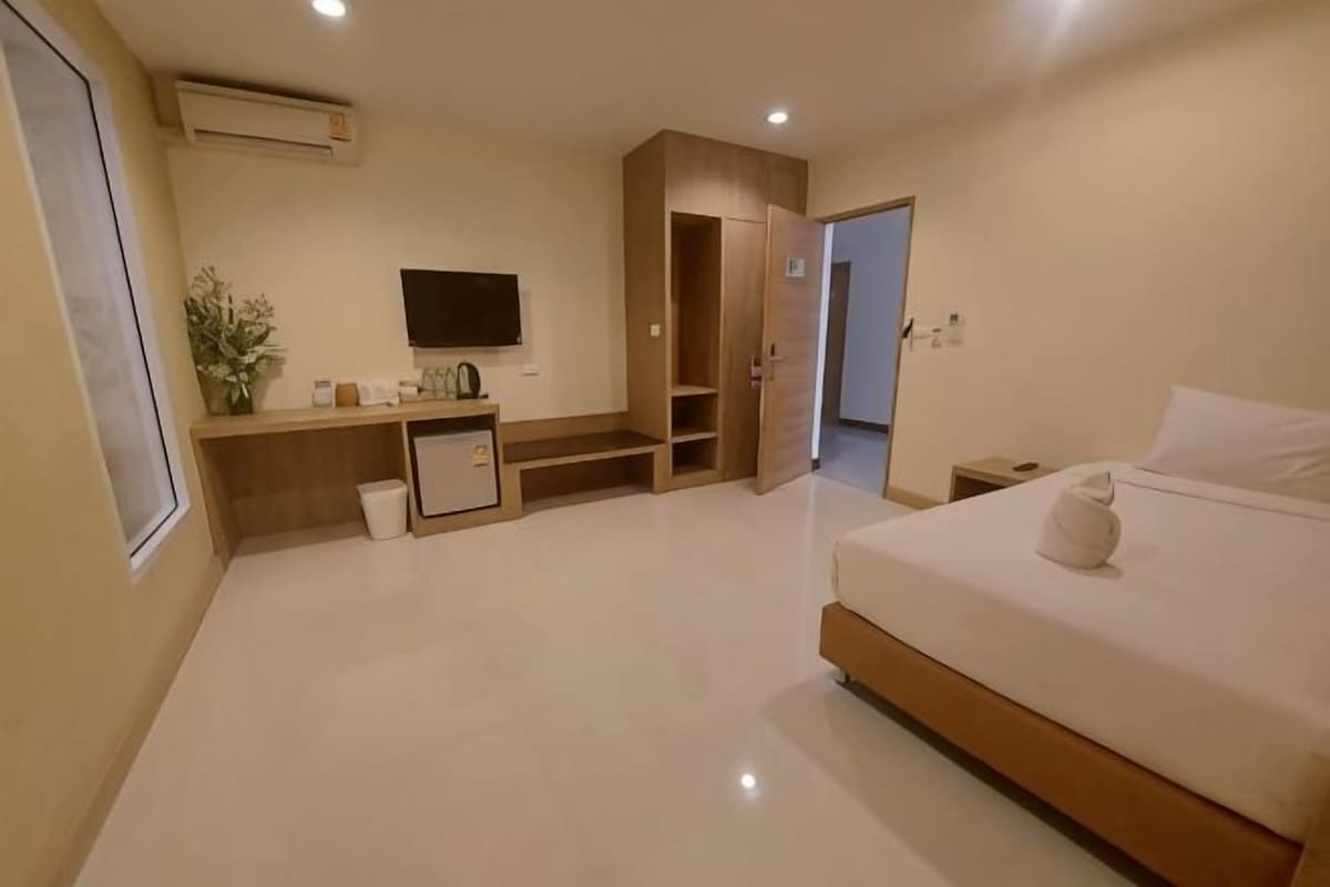 A hotel room with a bed, a TV, a small desk, and a wardrobe.