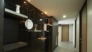 Un pasillo moderno con una paleta de colores blanco y negro, que presenta una puerta de madera, una pared blanca y una repisa con objetos decorativos.