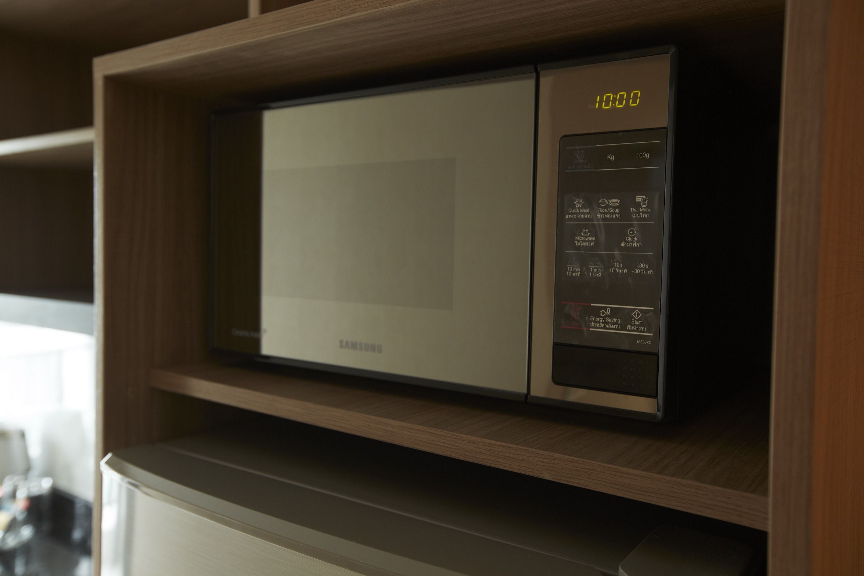 A Samsung microwave on a wooden shelf in a kitchen.