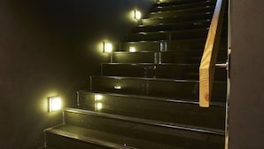 Una escalera con barandales de madera y apliques de luz en la pared.