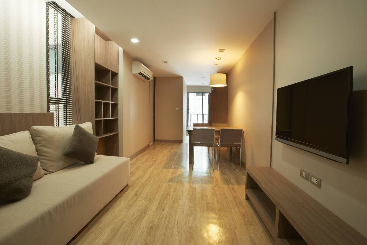 Una sala de estar moderna con un sofá, televisor y suelo de madera.