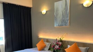 Une chambre d’hôtel avec deux lits, un tableau au mur et un vase rempli de fleurs.
