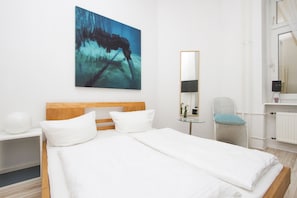 Ein Hotelzimmer mit einem großen Bett, einem Holzkopfteil, einem Nachttisch, einem Sessel, einem Spiegel und einem Bild an der Wand.