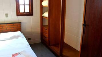 Una habitación pequeña y bien iluminada con una cama individual, un armario de madera y una ventana.