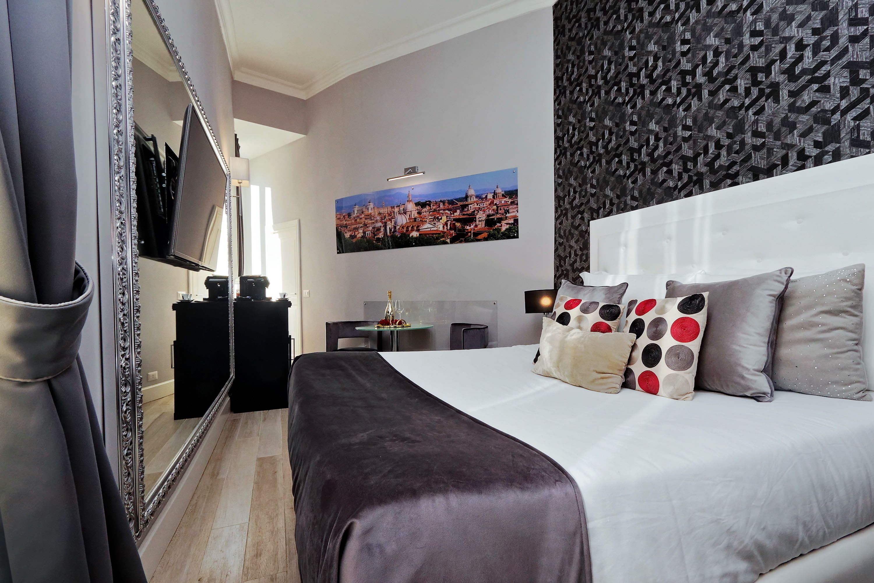 A hotel room with a large bed, a TV, a desk, and a cityscape painting on the wall.