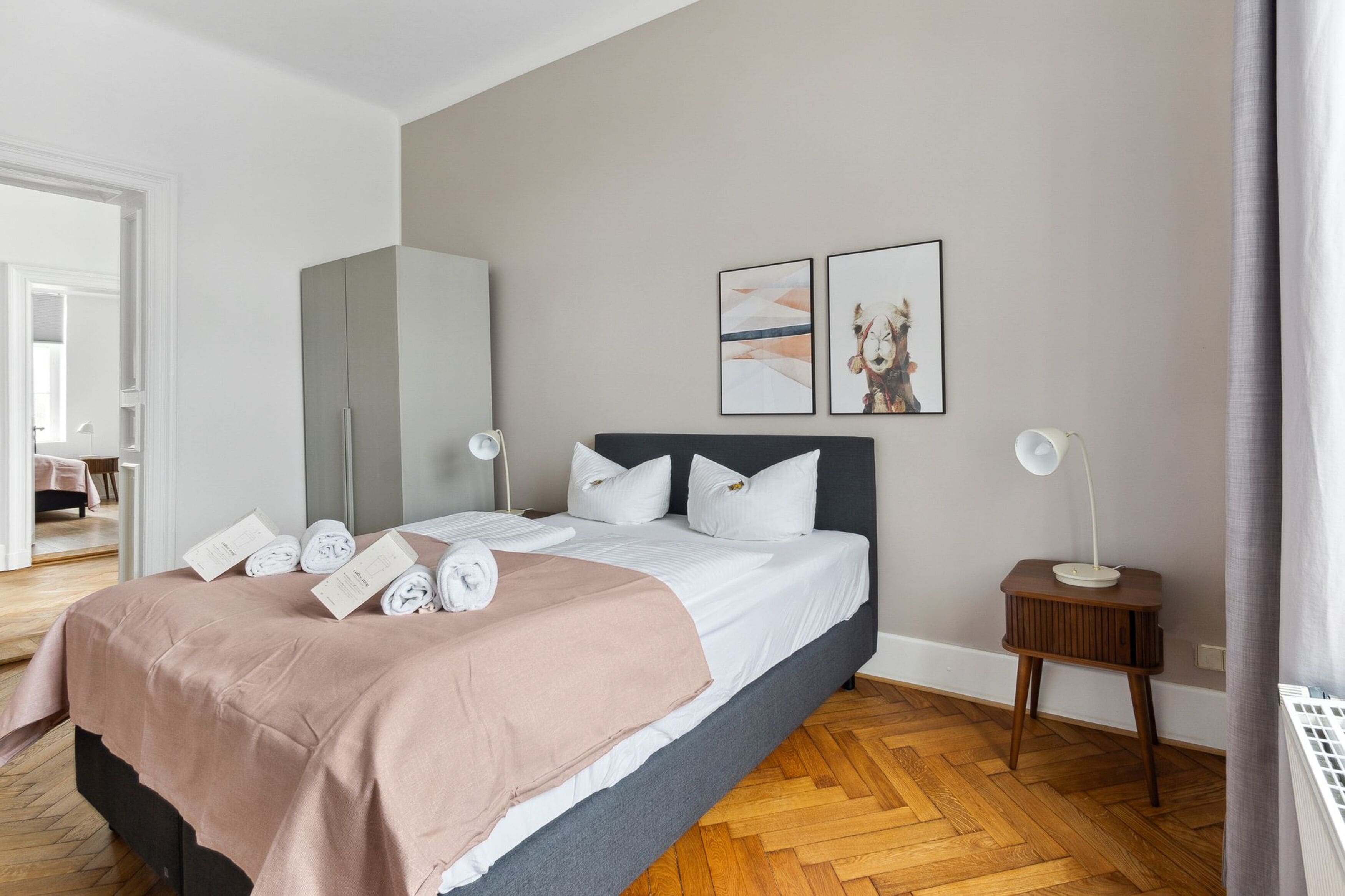 Une chambre à coucher moderne avec un lit, des tables de chevet et des œuvres d’art accrochées au mur.