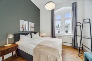 A neatly arranged bedroom with a bed, bedside tables, a window with curtains, and a radiator. - Limehome Dresden Antonstraße (Dresden)