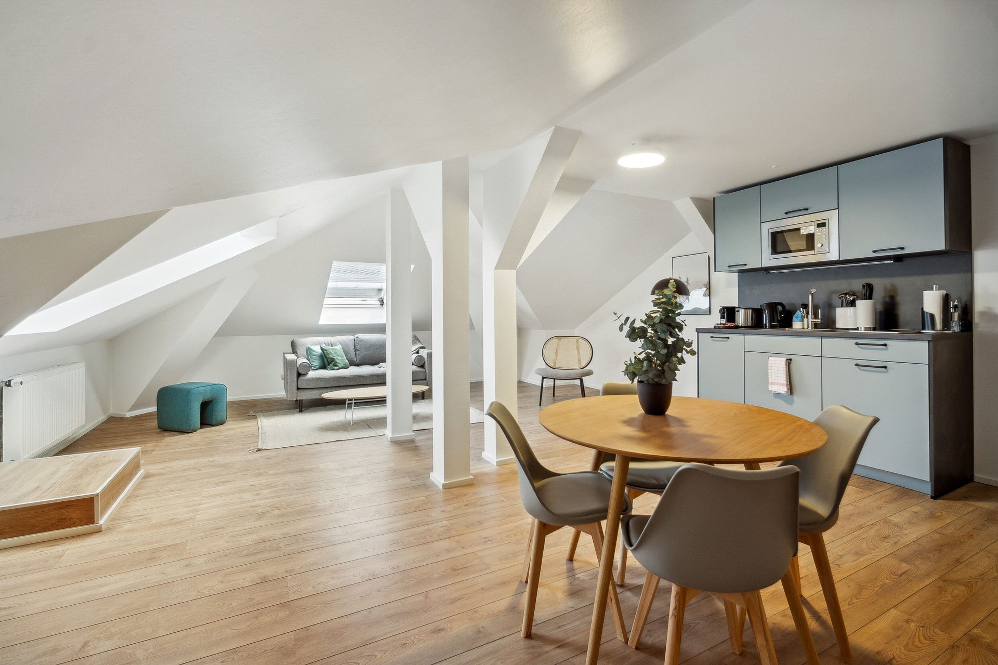 A modern loft apartment with a dining area, kitchen, and living space.