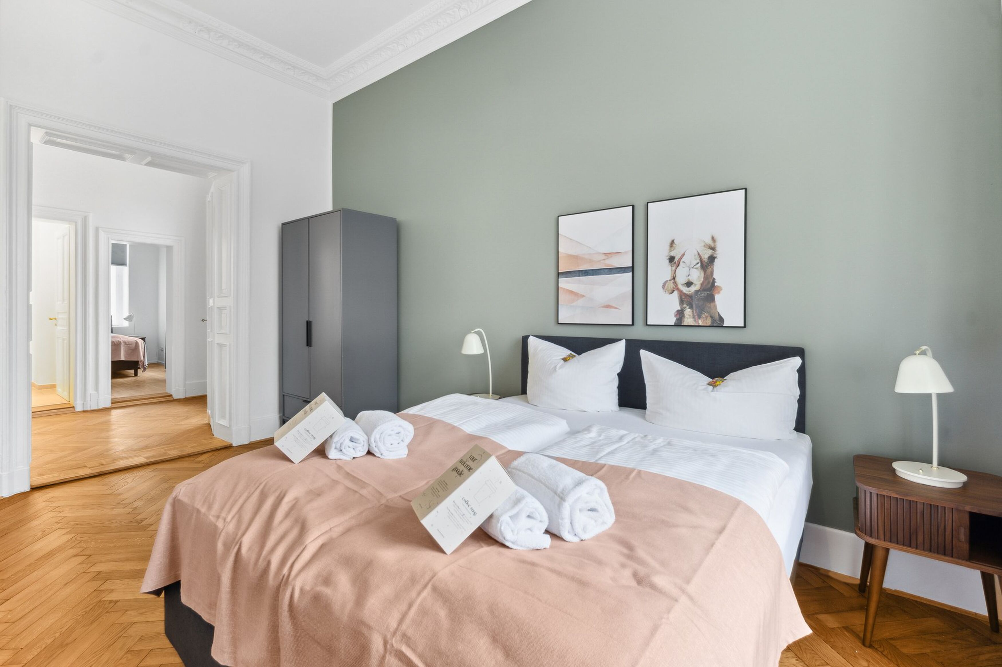 Une chambre d’hôtel avec un lit, une table de chevet, une lampe et deux tableaux encadrés au mur.