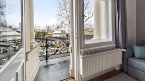 Une pièce avec vue sur un balcon, un radiateur et un canapé gris.