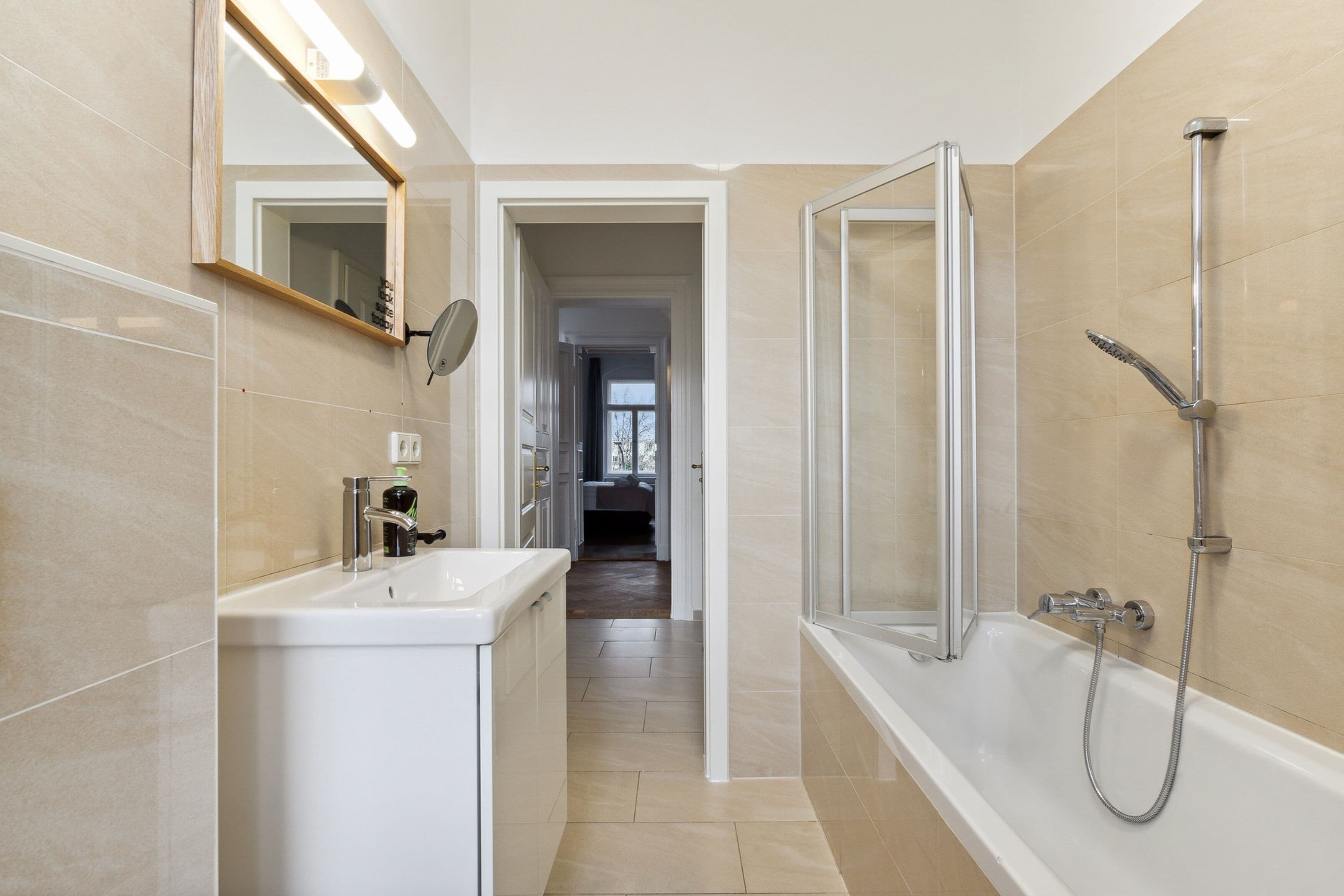 A modern bathroom with a bathtub, a sink, and a mirror.