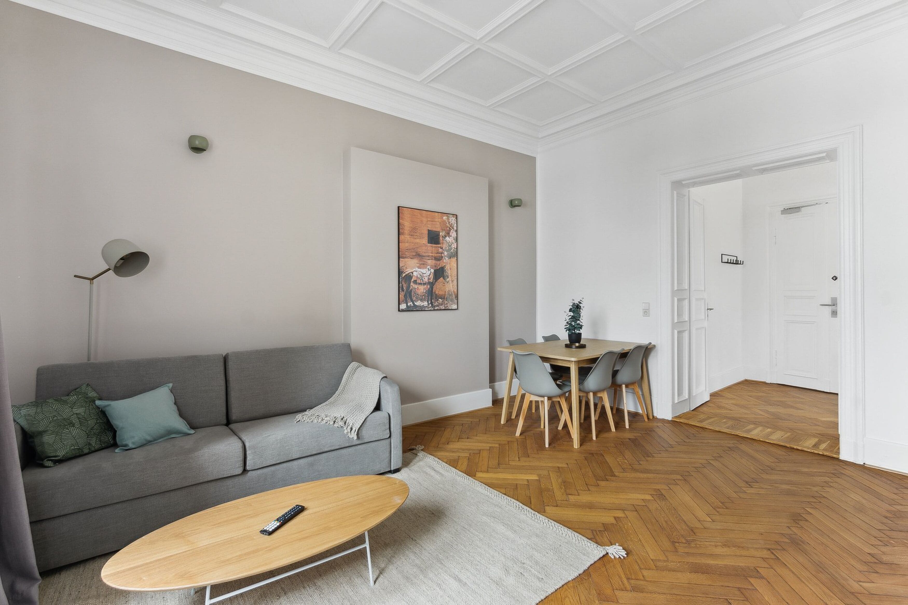 A living room with a sofa, coffee table, and dining area with chairs.