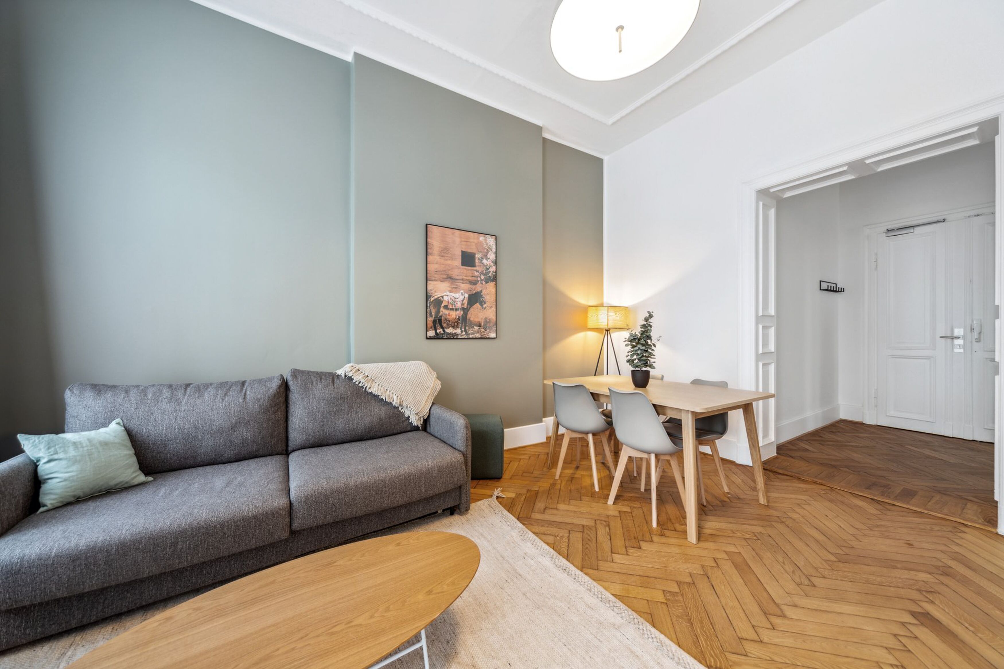 Un salon moderne avec un canapé gris, une table basse en bois et un coin repas comprenant une table et des chaises.