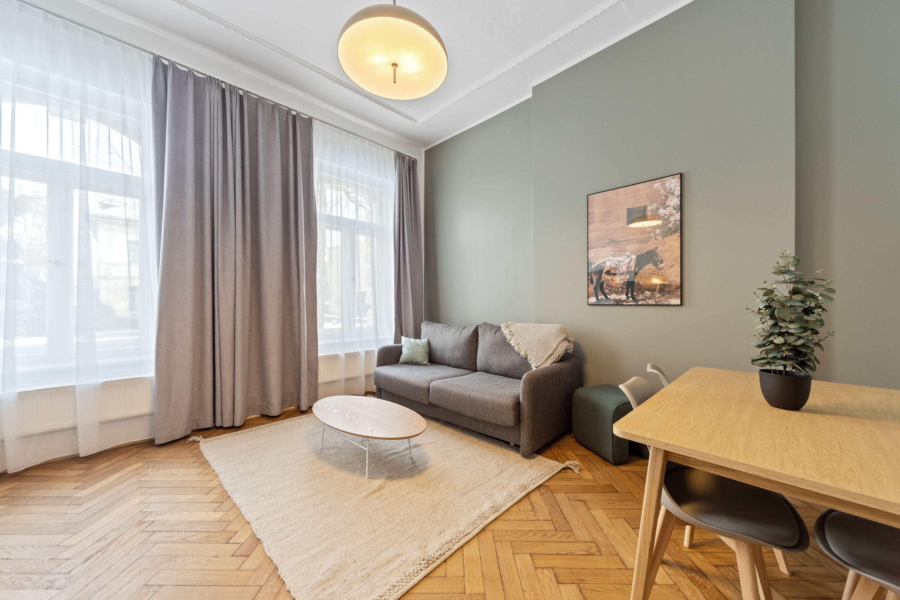 Ein modernes Wohnzimmer mit einer Couch, einem Couchtisch, einem Esstisch und einer Zimmerpflanze.