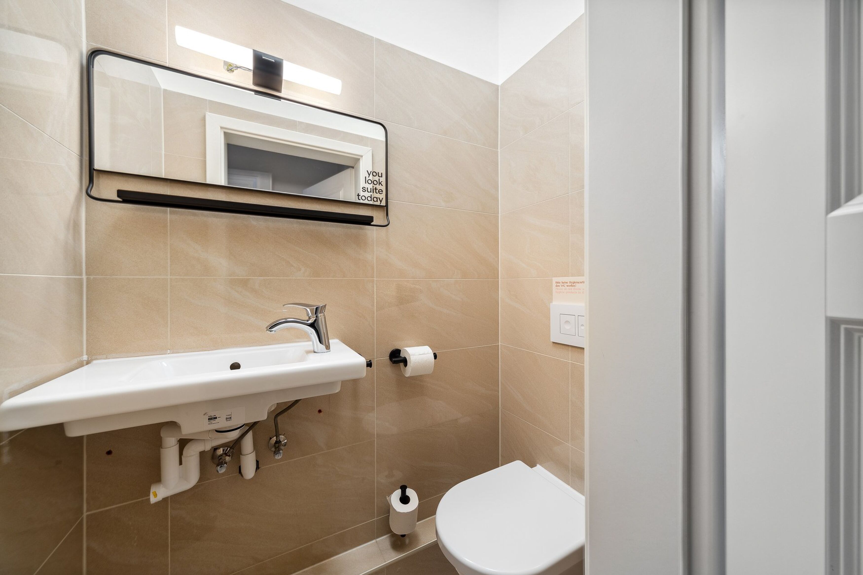 A bathroom with a white sink, a mirror, and a toilet.