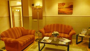 A lobby with two striped armchairs, a coffee table with magazines, a floor lamp, and a painting on the wall. - Hotel Wurms (Düsseldorf)