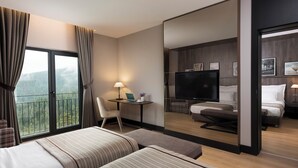 Une chambre d’hôtel avec deux lits, un bureau avec un ordinateur portable, une télévision et un balcon avec des rideaux.