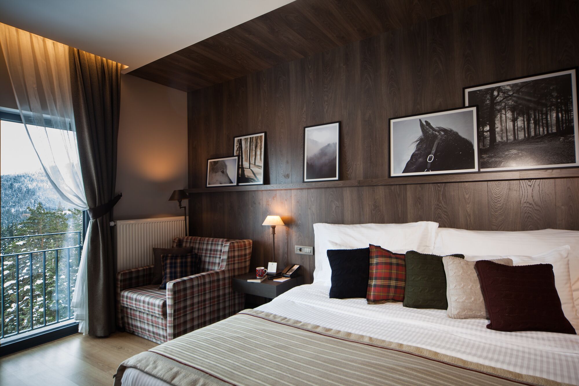 Une chambre d’hôtel avec un grand lit, une chaise, une table de chevet avec une lampe et des tableaux encadrés au mur.