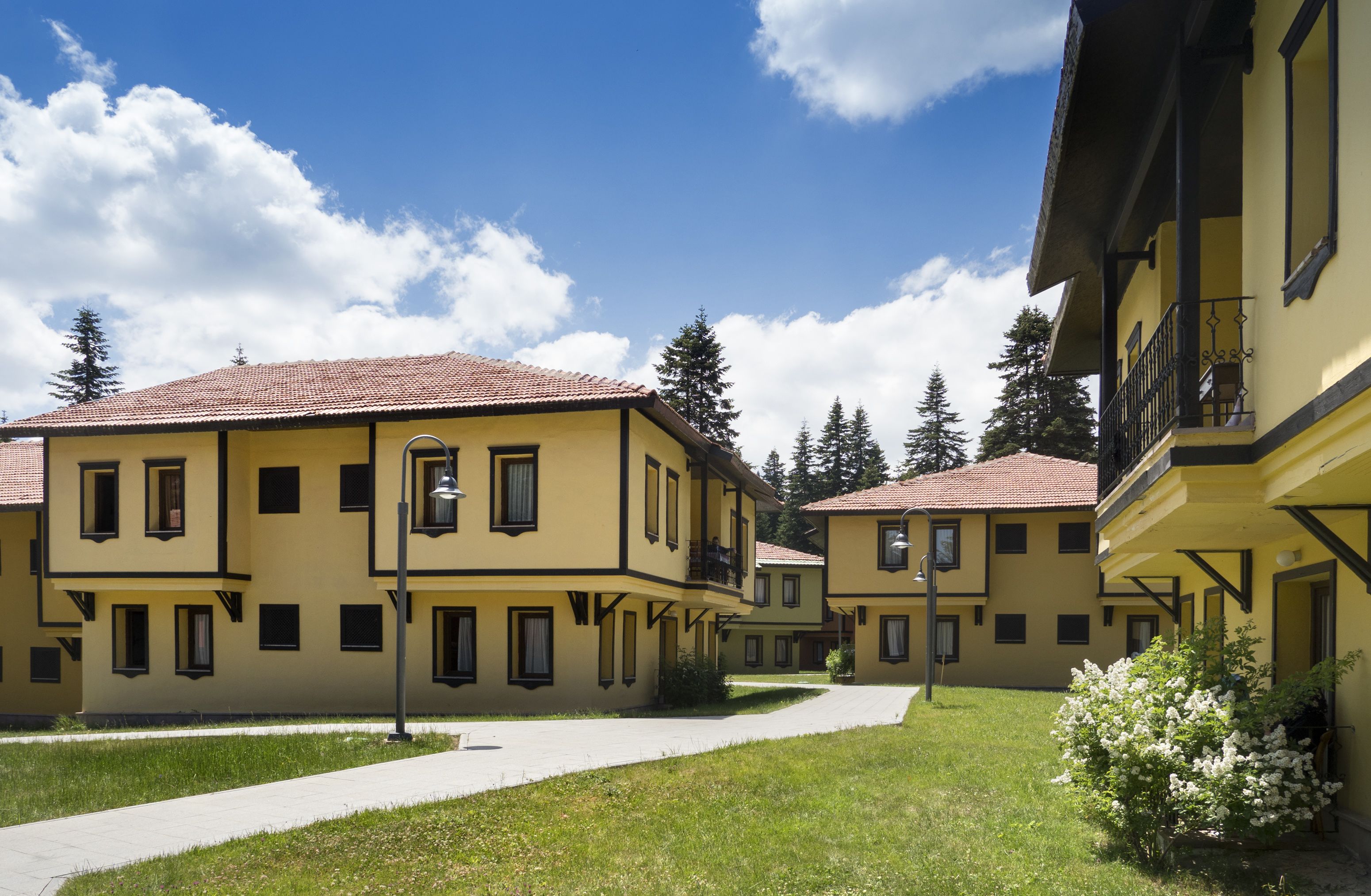 A courtyard with yellow buildings, a paved walkway, and green grass.
