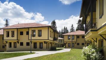 A courtyard with yellow buildings, a paved walkway, and green grass.