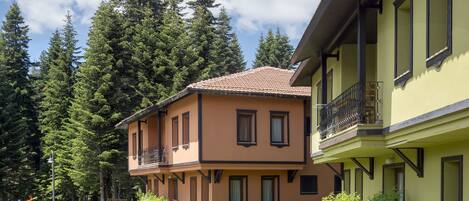 Ein zweistöckiges Gebäude mit Balkon und Garten.
