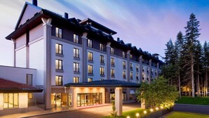 Un hôtel à plusieurs étages, doté d’un design moderne, avec un grand hall d’entrée agrémenté de portes en verre et d’un espace abrité.
