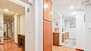 A hotel corridor with wooden flooring, a wooden cabinet, and a door with a green emergency exit sign. - Vacanze a Roma (Rome)