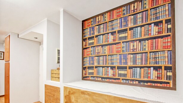 A room with a bookshelf filled with books, a wooden cabinet, and a white door. - Vacanze a Roma (Rome)