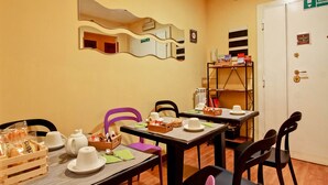 A dining area with tables set for tea service, a mirror on the wall, and a door marked "USCITA EMERGENCY". - Vacanze a Roma (Rome)