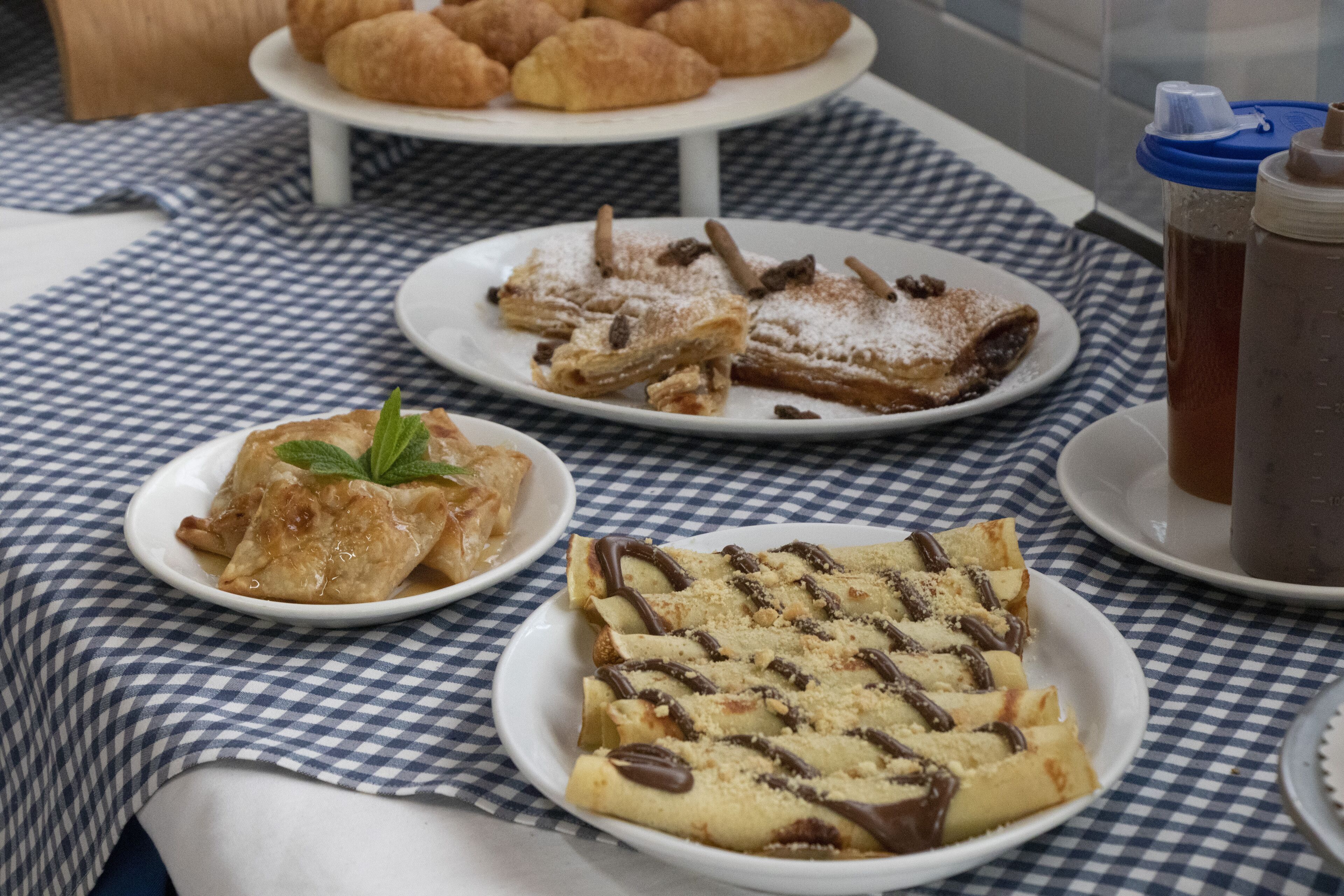 A table with a checkered tablecloth displaying various pastries and a beverage.