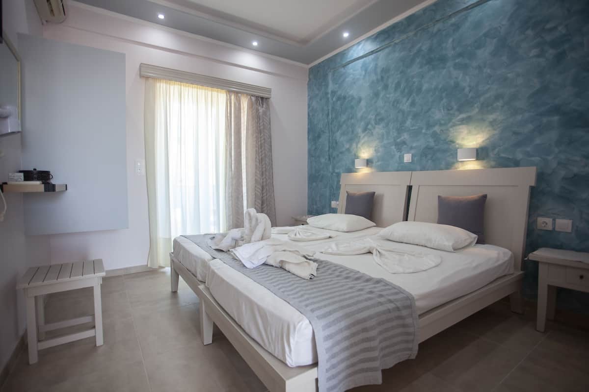 A bedroom with a bed, bedside tables, a nightstand, a window with curtains, and a wall with a textured design.