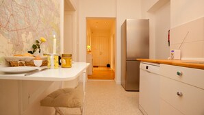 A narrow kitchen with a white countertop, a stainless steel refrigerator, and a map on the wall. - Lovely Flats Englische Straße (Berlin)