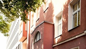 A street with red brick buildings, cobblestone pavement, and flower boxes on the windowsills. - Lovely Flats Englische Straße (Berlin)