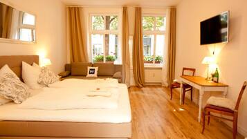 A hotel room with a bed, a desk, a chair, a TV, and large windows with curtains.
