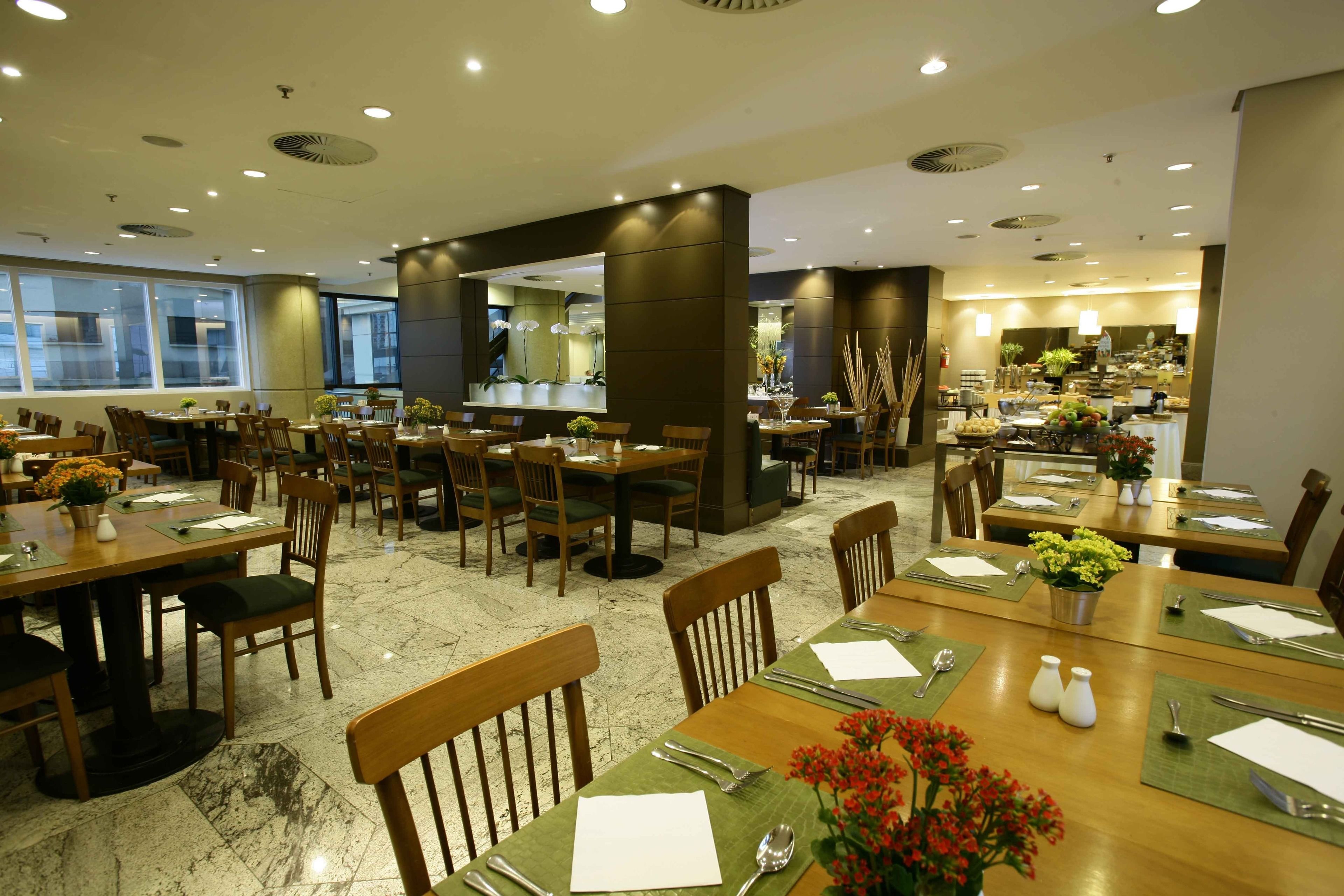 A spacious dining area with multiple tables and chairs, a central counter, and a view of the kitchen in the background.
