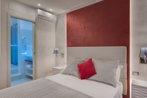 A modern bedroom with a large bed, a red accent wall, and a walk-in closet. - Shali Luxury Suite (Rome)