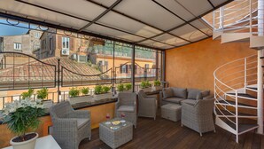 A covered outdoor balcony with wicker furniture, a spiral staircase, and potted plants. - Shali Luxury Suite (Rome)