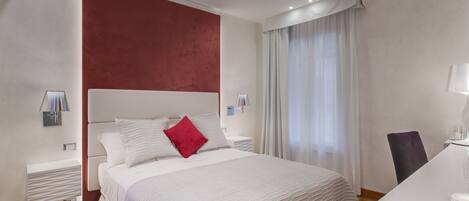 A modern hotel room with a large bed, a desk, and a chair.