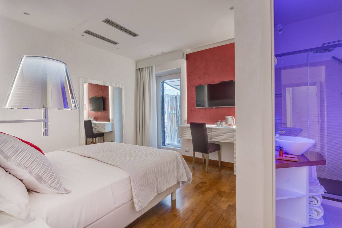 A modern hotel room with a bed, desk, and bathroom.