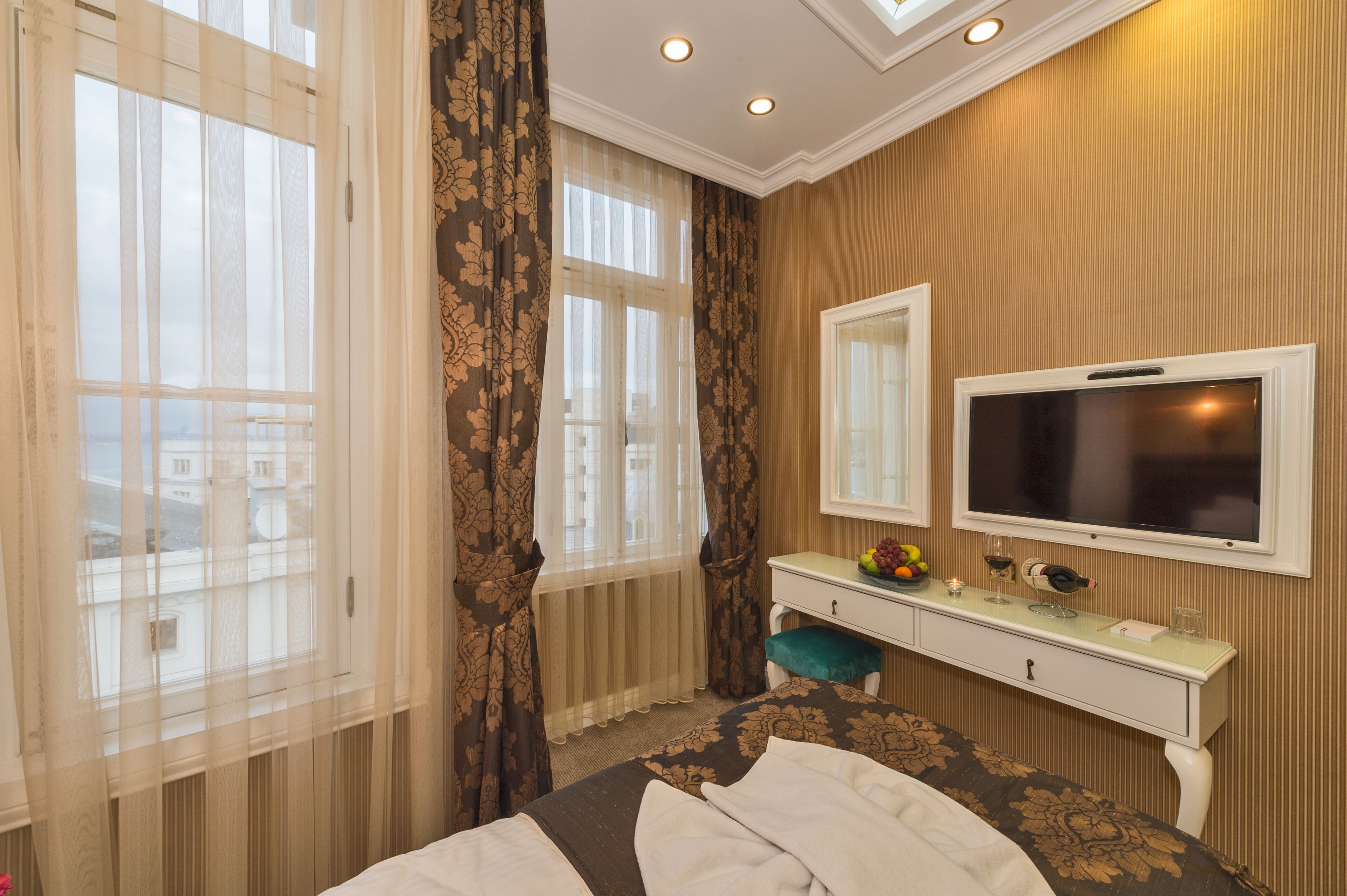 Una habitación de hotel con una cama, una tocador con espejo, un televisor y un ventanal con cortinas.