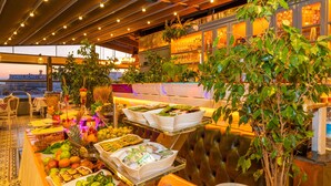 Un bufé con diversos alimentos y una planta grande en maceta.