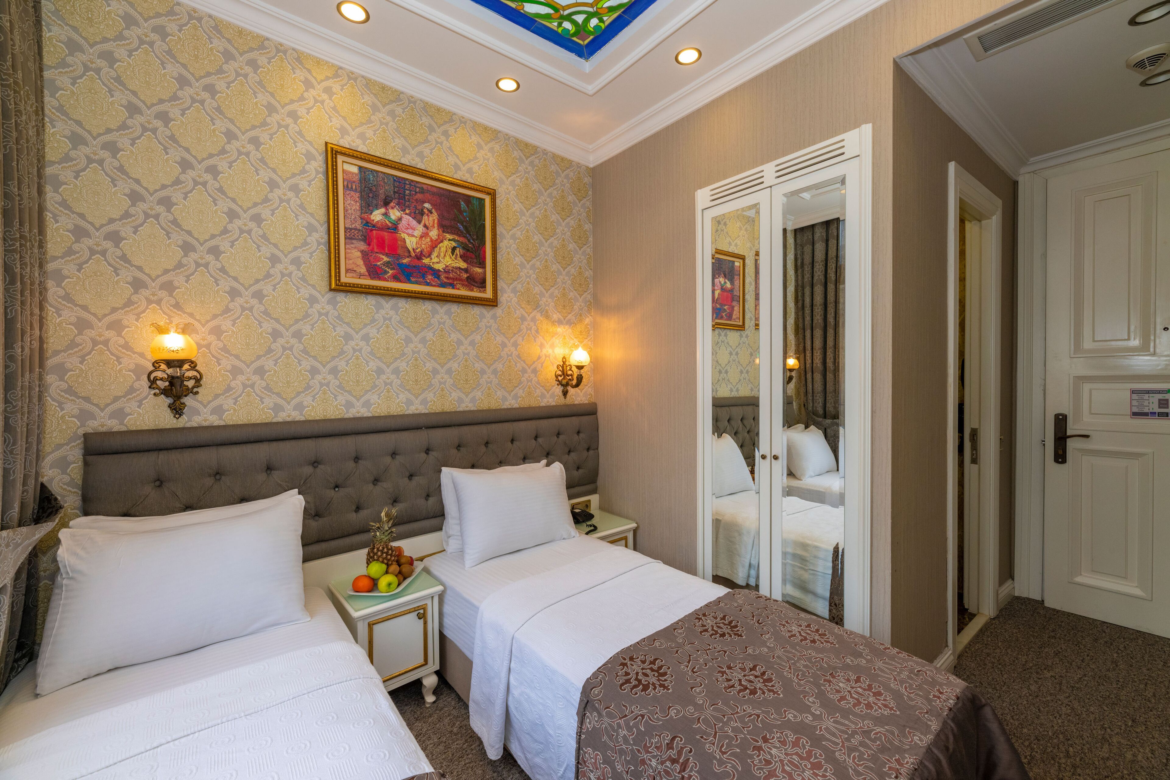 A hotel room with two beds, a large mirror, and a painting on the wall.