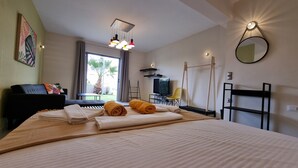 Una habitación de hotel con cama, escritorio, silla, televisor y ventana con cortinas.