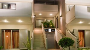 Un edificio moderno con una escalera central, un pequeño jardín y una entrada bien iluminada.