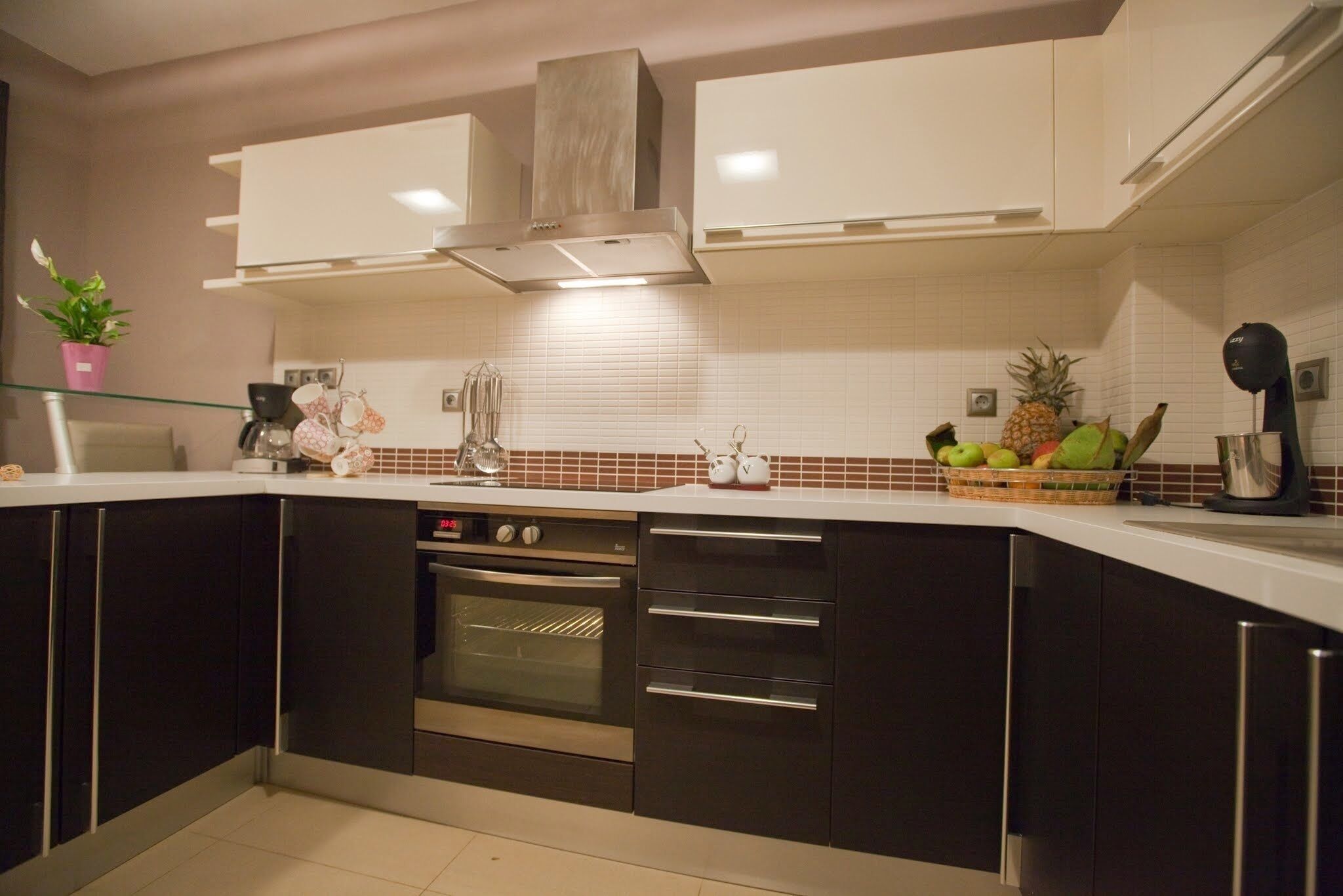 Uma cozinha moderna com armários escuros, eletrodomésticos de aço inoxidável e painel de azulejos brancos.