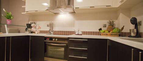 Uma cozinha moderna com armários escuros, eletrodomésticos de aço inoxidável e painel de azulejos brancos.