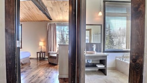Une chambre avec un plancher en bois, un lit, une table de chevet et une lampe.