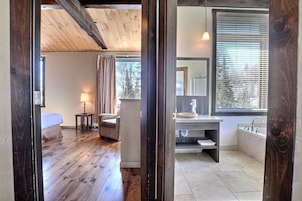 Dormitorio con piso de madera, una cama, una mesita de noche y una lámpara.