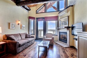Una sala de estar acogedora con chimenea, suelo de madera, un sofá, un sillón y un televisor.