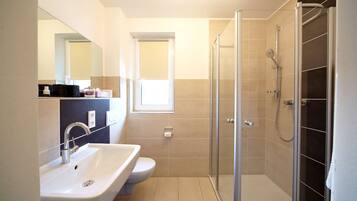 Ein modernes Badezimmer mit Waschbecken, Toilette und einer Duschkabine.
